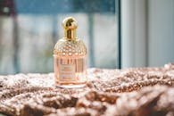 Elegant Guerlain perfume bottle on a textured fabric with natural lighting, exuding luxury and fragrance.